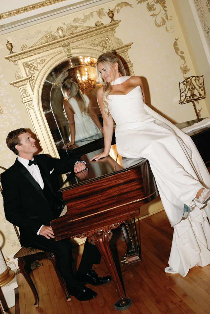 Bride and groom pose with piano at Grand Island Mansion