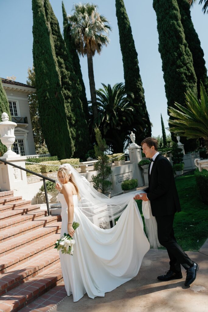 Groom carries bride's dress train at Grand Island Mansion