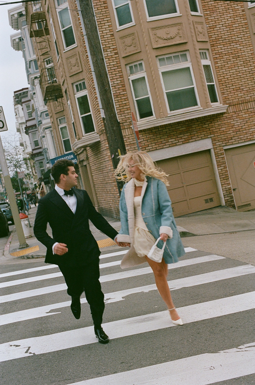 Couple runs across the street during engagement photoshoot in San Francisco