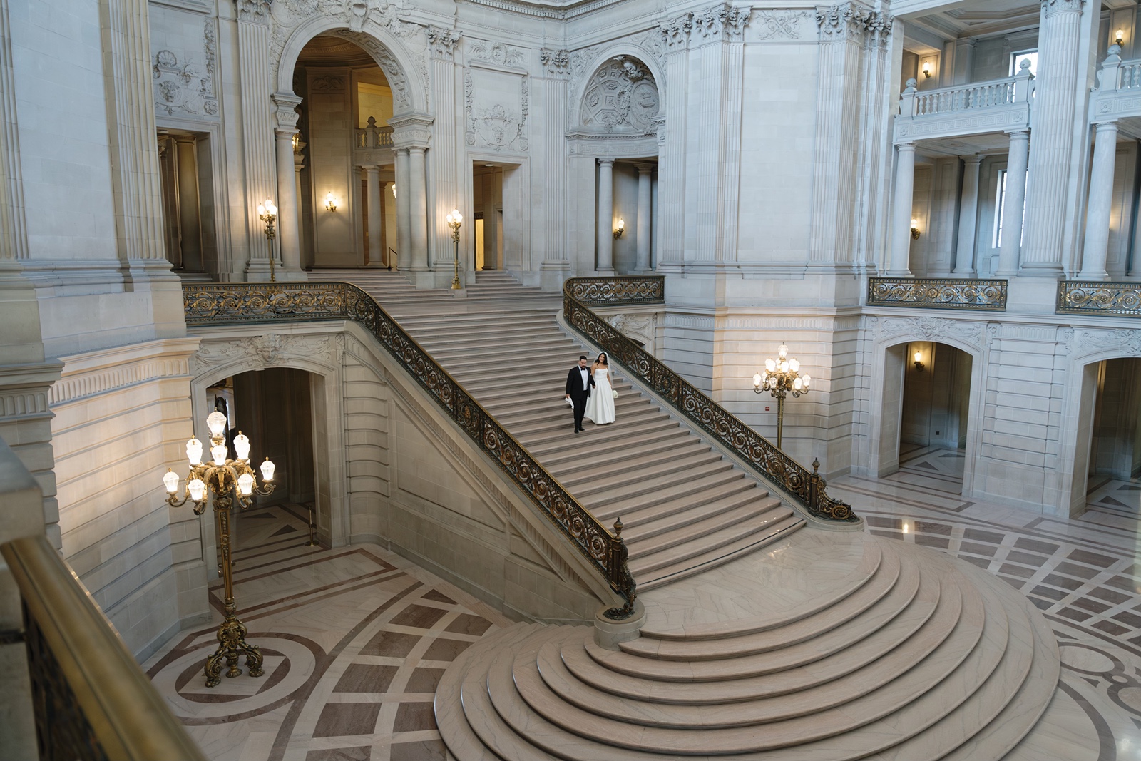 Bride and groom on staircase at San Francisco City Hall